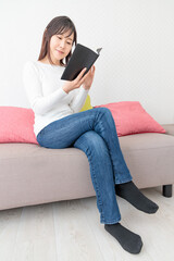 Woman sitting on the couch and reading a book