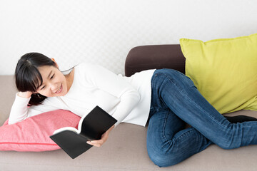 Woman lying on the sofa reading a book