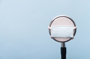 Medical stethoscope in a face protection mask on light blue background. Creative concept new...