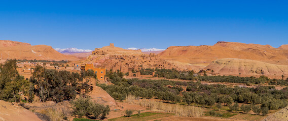 Amazing panoramic view of clay houses and the Kasbah (fortress) in the ancient town of Aid Benhaddou, Morocco with Atlas mountains in the background