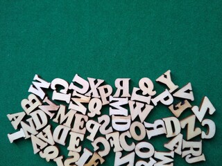 wooden letters of the alphabet scattered on a green background with space for text. High quality photo