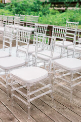 Modern ceremony in European style. Transparent plastic chairs with a padded base for guests stand against the wedding arch.