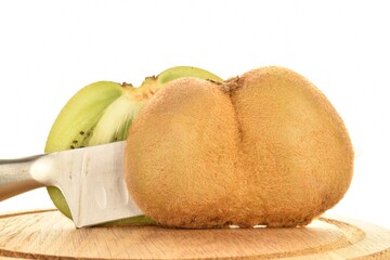 Two halves of natural organic kiwi fruit with metal knife on a round wooden tray, close up, isolated on white.