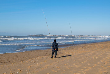 vendée, France; January 25, 2021: a fisherman and his lines on a beach in Bretignolles Sur Mer and enjoying the good weather.
