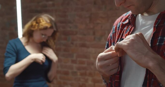 Male and female bloggers adjusting small lavalier microphone on clothes before filming video