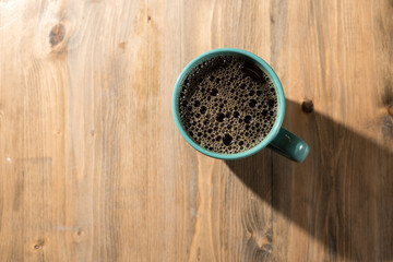 Obraz na płótnie Canvas Green coffee mug casting on wooden table. 