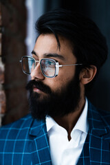 Portrait of a handsome man with a beard and mustache wearing glasses and a plaid jacket