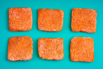 Orange bricks of frozen grated carrots. Procurement of frozen food. Semifinished
