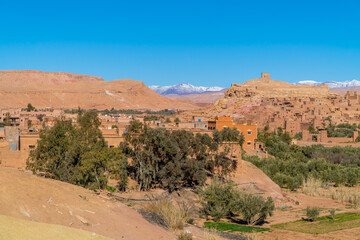 Fototapeta na wymiar Beautiful Panoramic view of clay houses and the Kasbah (fortress) in the ancient town of Aid Benhaddou, Morocco with Atlas mountains in the background
