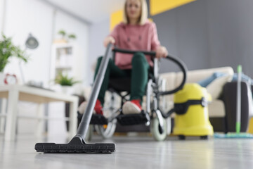 Woman in wheelchair vacuuming floor at home closeup