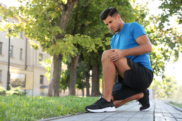 Man in sportswear having knee problems outdoors