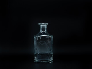 Single empty glass bottle on a black background. Transparent square bottle. Front view of the vertical staying colorless jar.