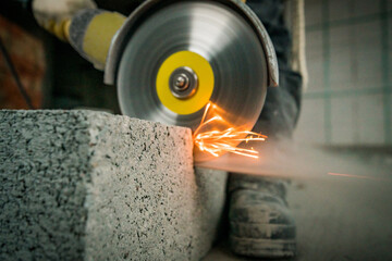 a builder saws a building block with a grinder