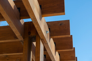 An abstract geometric composition of brown wooden planks against a blue sky.