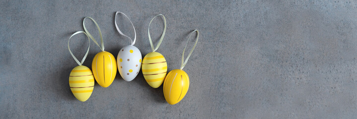 Banner copyspace. Easter colorful yellow eggs in a row with ribbons on the grey background with copy space. Flat lay. Top view