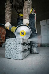 a builder saws a building block with a grinder