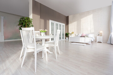 Luxurious and expensive interior of an open-plan apartment in light colors. Stylish modern bedroom with minimal design, dining area and guest space.