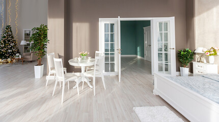 Luxury rich expensive apartment interior in light colors. Stylish contemporary minimalistic design. Full of sun light. A lot of space decorated with Christmas tree