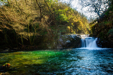 Preciosa cascada acaba en un maravilloso estanque iluminado por el sol brillando con sus turquesas...