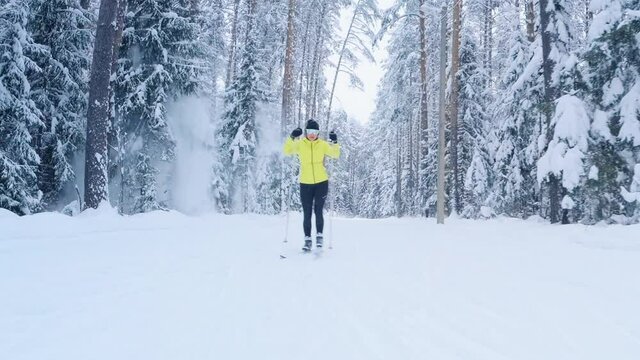 Cross country ski. Woman skier works out on the skating ski track in the winter forest with snow covered trees