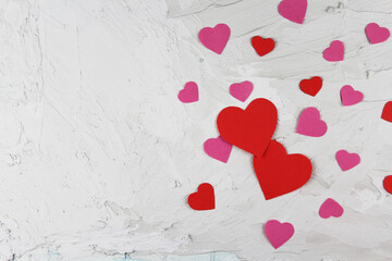 Valentine's day red and pink paper hearts of various sizes on light concrete background flat lat composition mokup ready