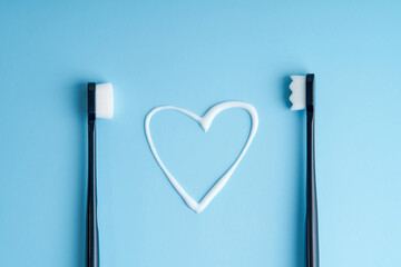 Heart shaped toothpaste between two toothbrushes close up