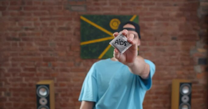Young caucasian man holding condoms with stop aids inscription on wrap