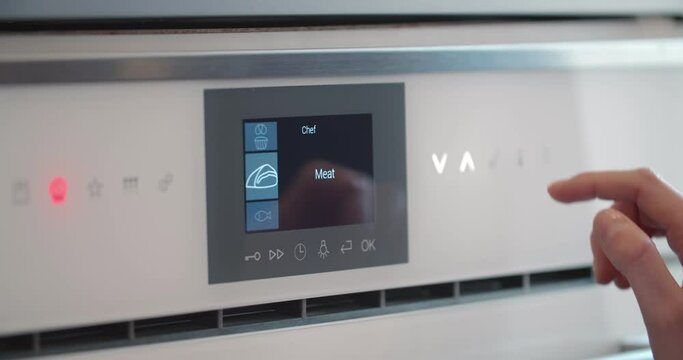 Close up of woman pushing buttons on touch panel of microwave or oven.