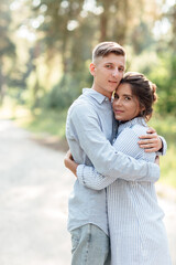 Cheerful young woman and man are hugging outdoors in summer park. couple in love having date and romantic vacation on sunny day. Love and relationships between young people