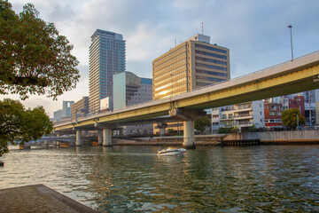 Fototapeta na wymiar Osaka - cityscape and river O and speedboat. Spring coming - time of sakura!