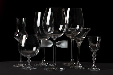 Alcohol glasses with bow tie isolated on black background. International Bartenders Day.