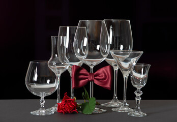 Alcohol Glasses with bow tie and flowers isolated on black background. International Bartenders Day.