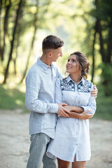 Obraz premium Outdoor shot of young happy couple in love on sunny day on nature. Man and woman hugging, sunlight in summer park. valentine's day. The concept holiday