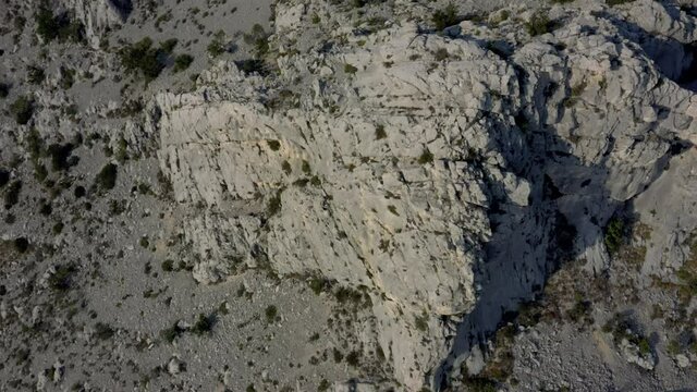 Aerial revealing shot of a motor road with cars in the Croatian coast. Drone flying over the rocky mountains on a top down view.