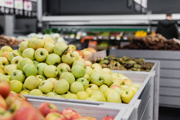 Fresh apples near groceries on blurred background in supermarket
