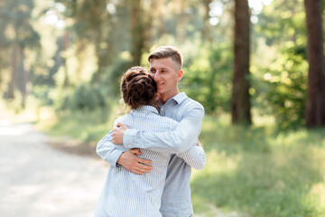 Fototapeta premium Cheerful young woman and man are hugging outdoors in summer park. Dating and romantic vacation. couple in love gently looking at each other on sunny day. Love and relationships between young people