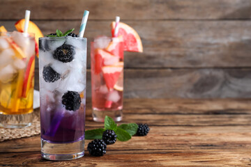 Delicious blackberry lemonade made with soda water and fresh ingredients on wooden table. Space for...