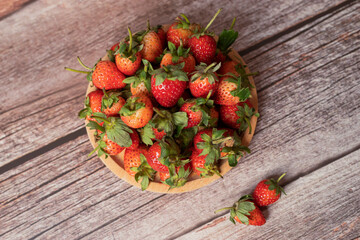 Several strawberries in a wooden tray on a wood grain table