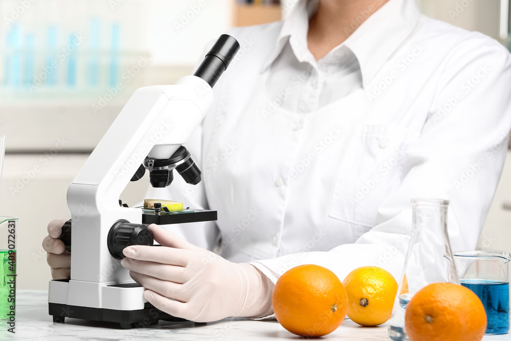 Wall mural scientist inspecting slice of apple with microscope in laboratory, closeup. poison detection