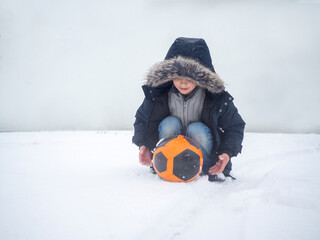 Fototapeta na wymiar boy playing in the snow with soccer ball