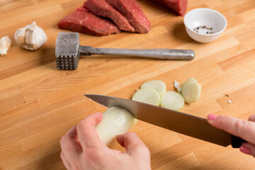 The process of cooking. Slicing onions. The woman's hands hold a knife and a shallot bulb. Hammer...