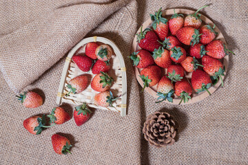 Several strawberries in a wooden tray on a brown cloth