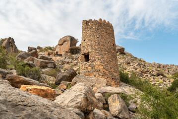 Tower ruins with Omani flag into the hills of the old village Misfat Al Abriyeen, Sultanate of Oman