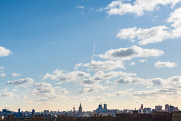 airplane flies in white clouds in a blue sky and leaving trail