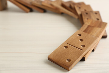 Fallen wooden domino tiles on white table, closeup