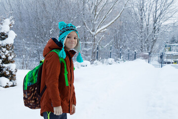 View on a child from behind with a school bag on the way to school in winter