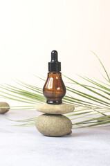 Essential natural oil in a brown bottle on a stone. Cosmetic product in a bottle with a pipette on a beige background. Natural organic spa cosmetic beauty concept