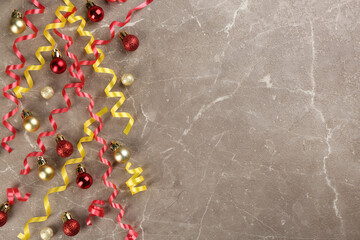 Colorful serpentine streamers and Christmas balls on grey background, flat lay. Space for text