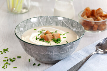 Cream soup in bowl on white wooden background. Rustic, country style.