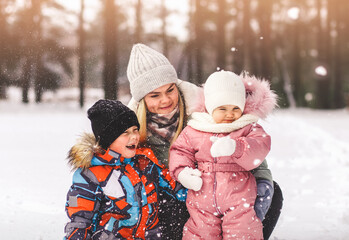 Fototapeta premium Mother with son and daughter in a snow park in winter